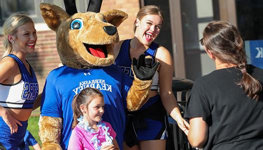 a child poses with unk cheer leaders and louie the loper